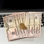 A pile of dollars on a laptop