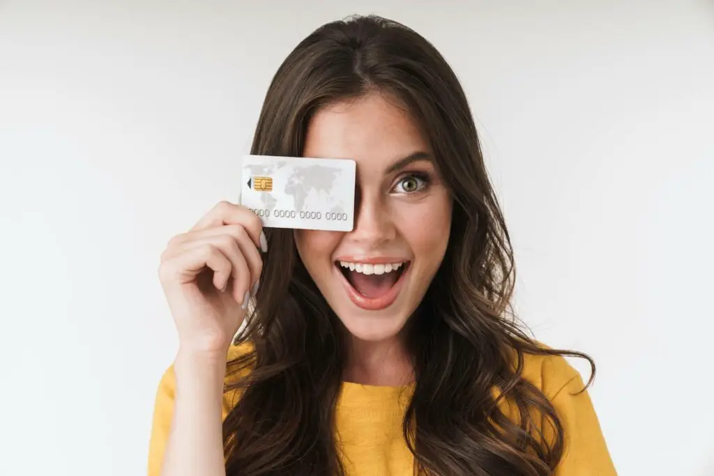 A girl joyfully holding her PayPal debit card close to her face