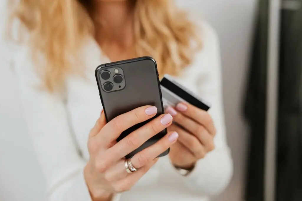 A woman holding an iPhone and a card
