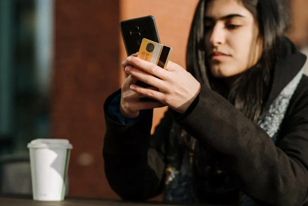 Woman holding a card and looking at a smartphone