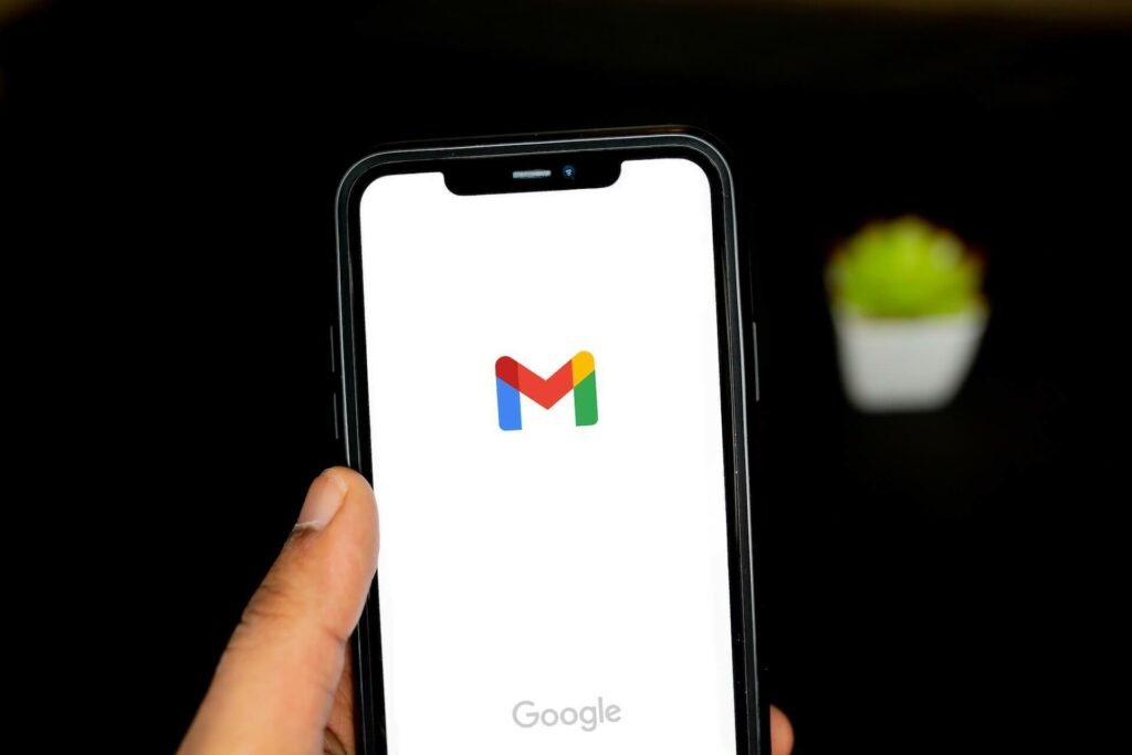 Person holding a phone with a Gmail logo on it

