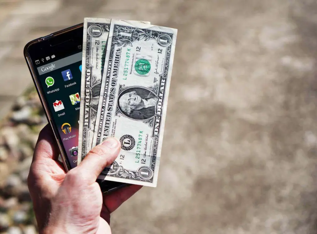 Person holding a phone and dollars