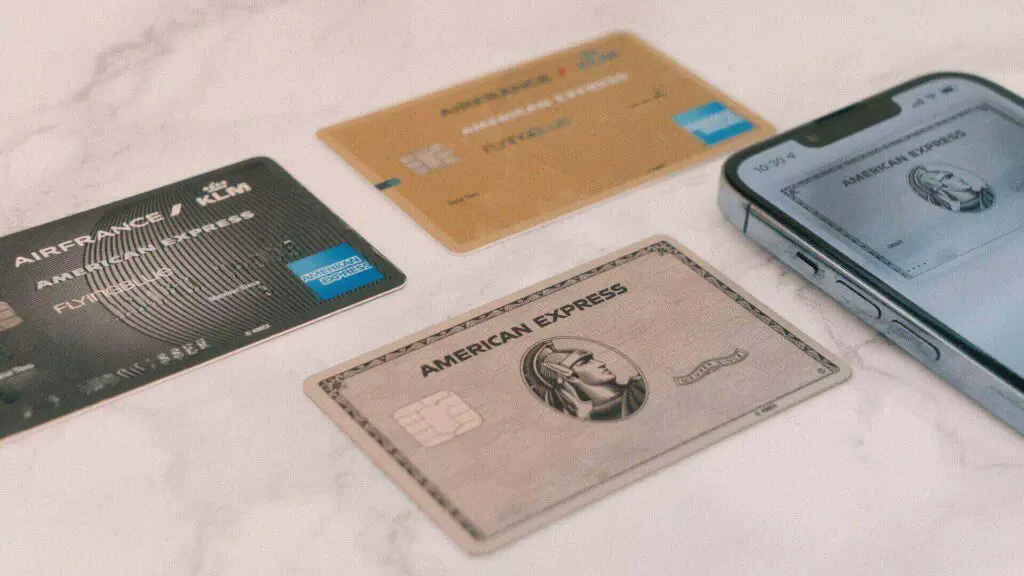 Credit and debit cards on a marble surface next to a smartphone