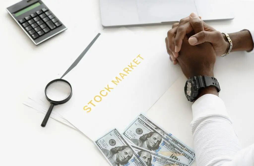 A person's hands on the table with money and sign stock market  